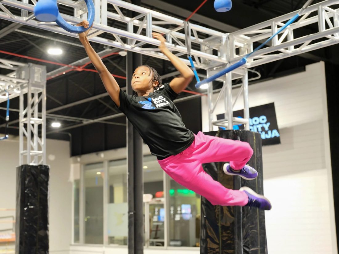ROC City Ninja athlete swinging between grips on the rig